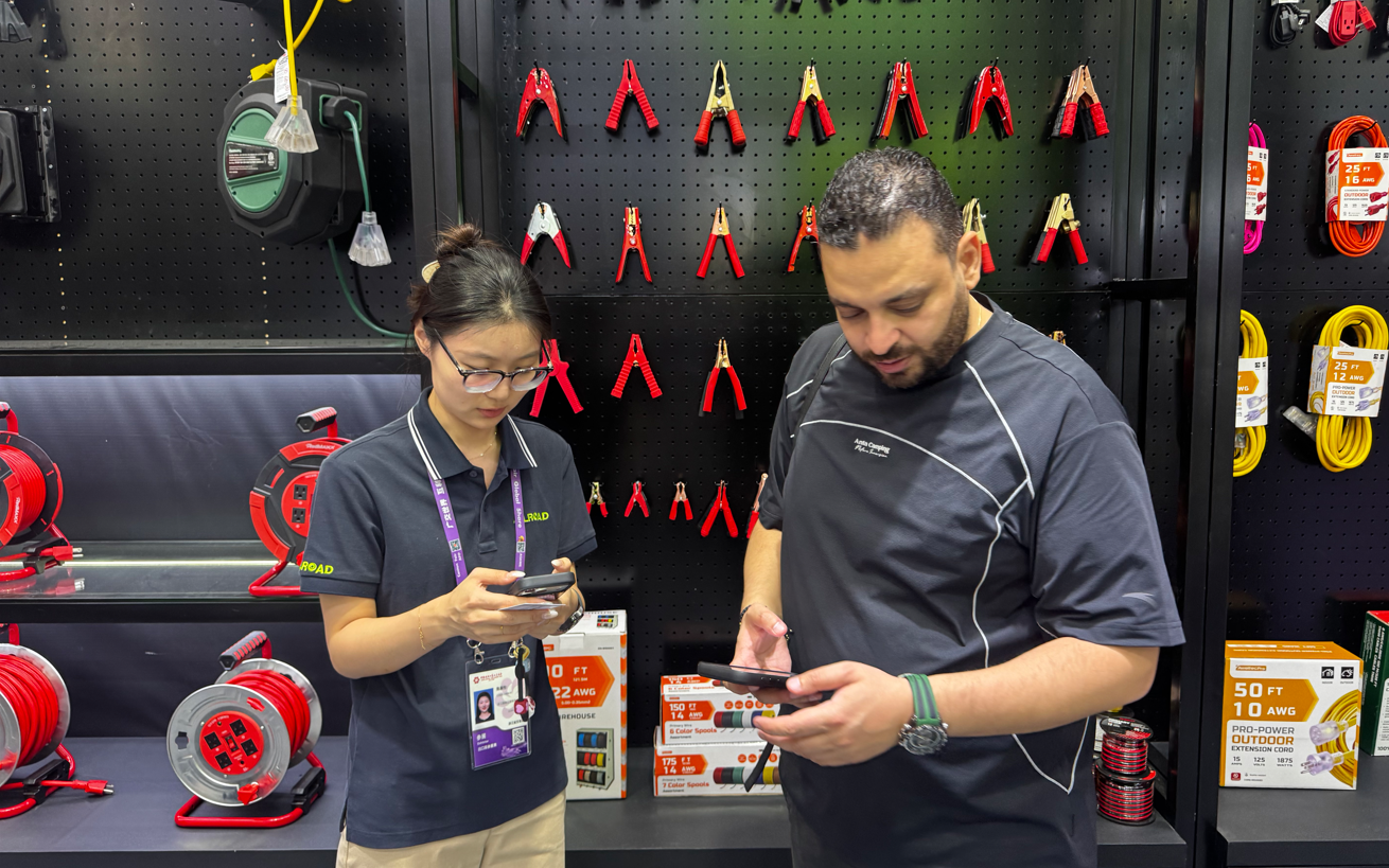 An ALLROAD team member discussing jumper cables and extension cord reels with an overseas buyer