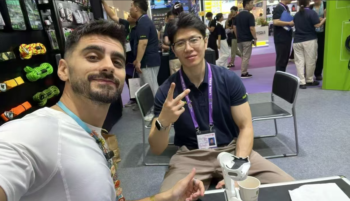 A buyer and an ALLROAD team member pose for a photo at the booth