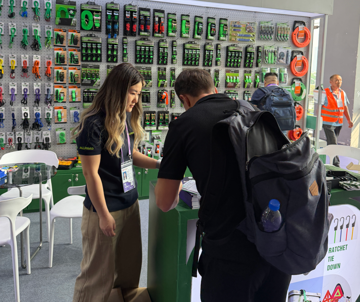 A buyer reviewing the ratchet strap and cargo control display wall with an ALLROAD team member