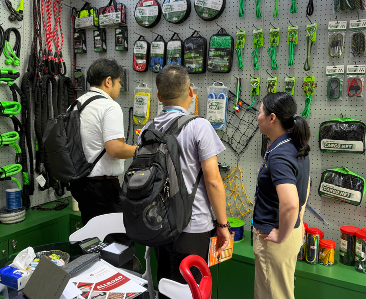 Buyers examining tow ropes, bungee cords, and cargo nets with an ALLROAD team member